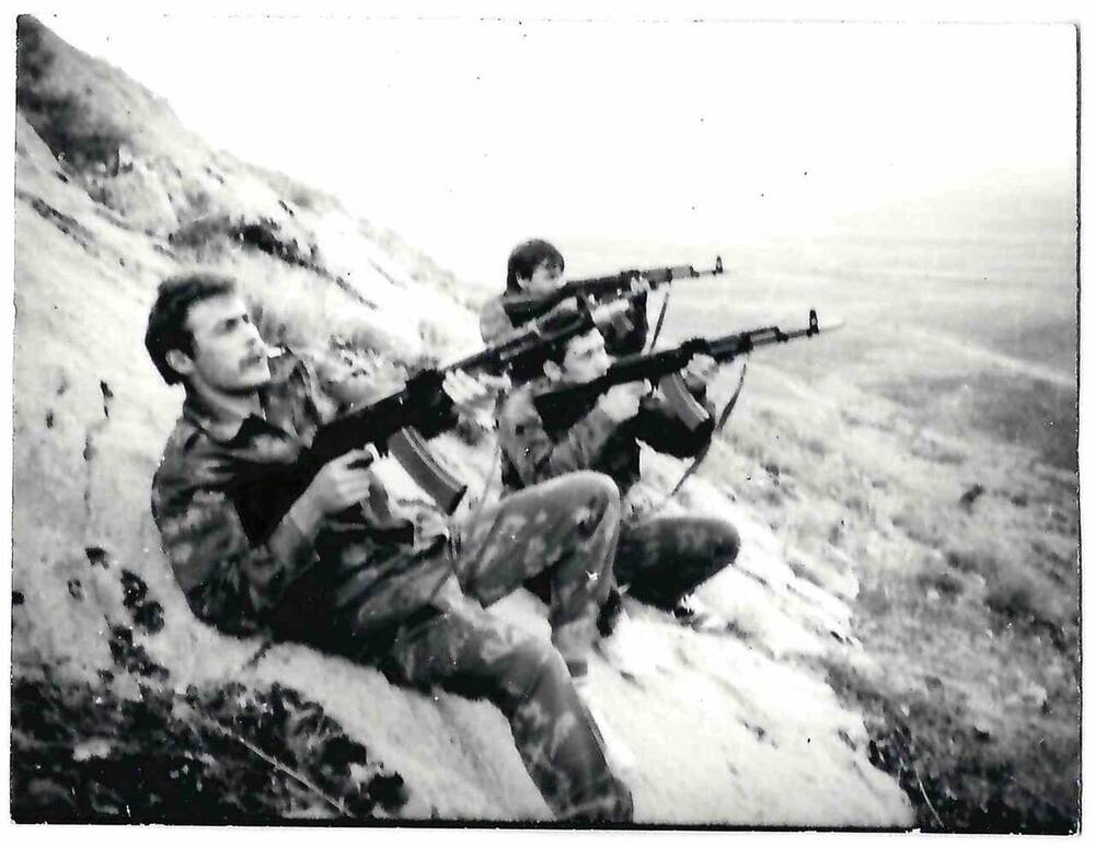 Фотография черно-белая. Изображены трое военнослужащих на холме.