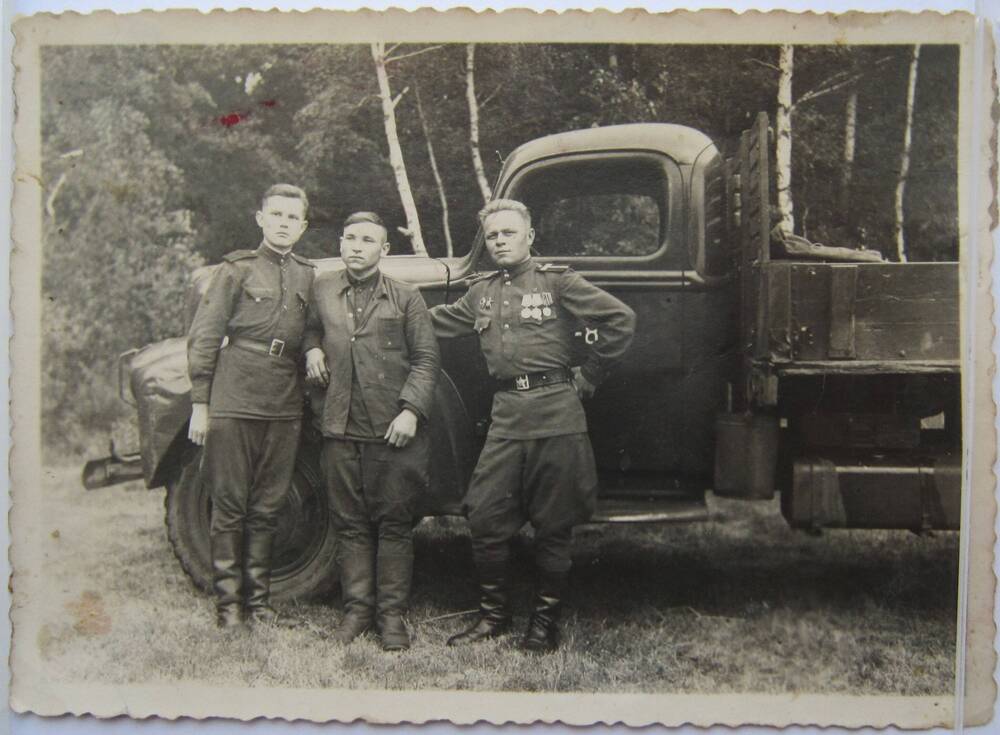 Фотоснимок. На фото трое мужчин, двое из которых в военной форме. Мужчины стоят у грузовика. На заднем плане виден лес и берёзы, 39-40-е гг.
Коллекция фотографий 40-50-х годов, собранная 
Березнёвой М. А.