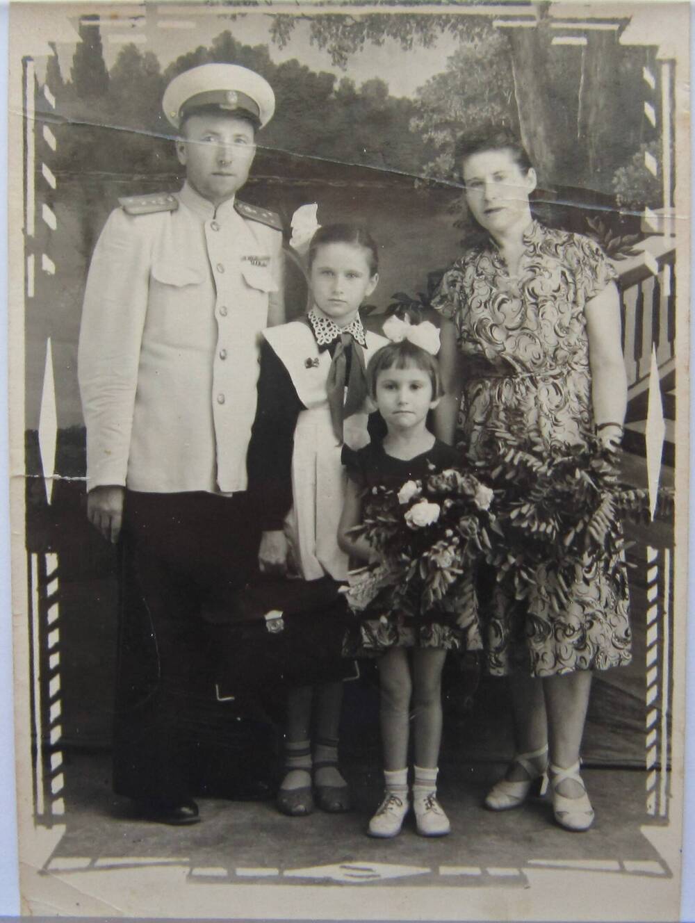 Фотоснимок. На фото семья из 4-х человек-отец, мать и двое девочек. Отец в парадной форме офицера, старшая девочка в школьной форме с белым фартуком. 1957 г. СССР.
Коллекция фотографий 40-50-х годов, собранная 
Березнёвой М. А.