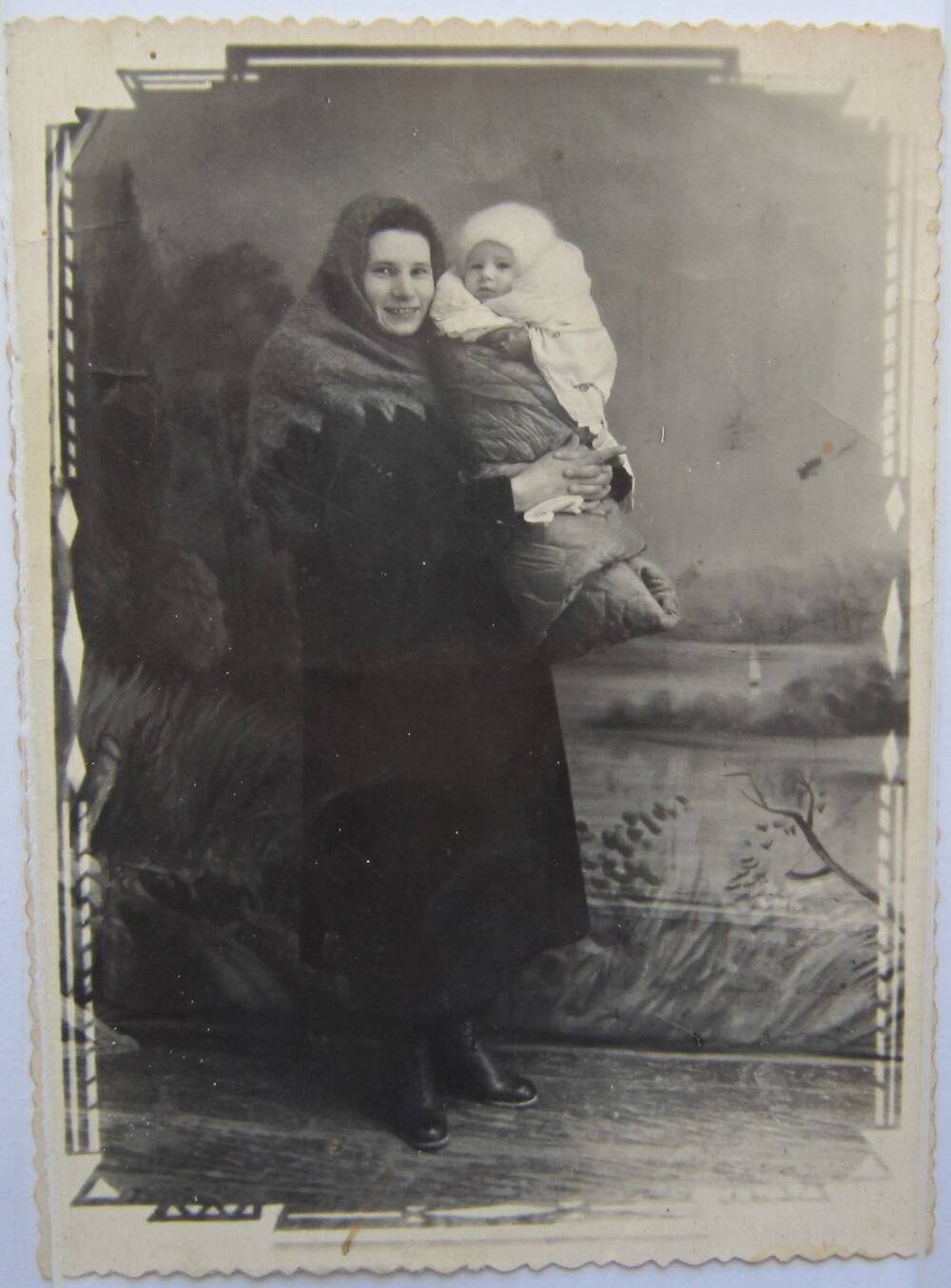 Фотоснимок. На фото женщина в верхней одежде. На голове теплый платок. На руках у женщины маленький ребёнок закутанный в одеяло.1940-е гг.   
Коллекция фотографий 40-50-х годов, собранная 
Березнёвой М. А.