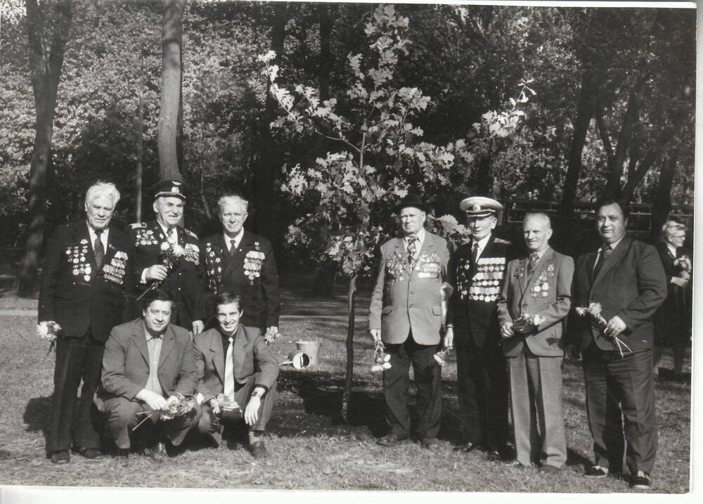 Фото ч/б, глянцевое, групповое. 9 ч-к ветераны и молодёжь на фоне посаженного дерева в г. Ленинграде.
