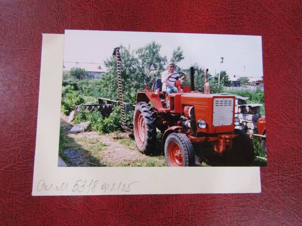 Фотография Чебаков В.П. летом, за рулем трактора, позади кустарники и дома
