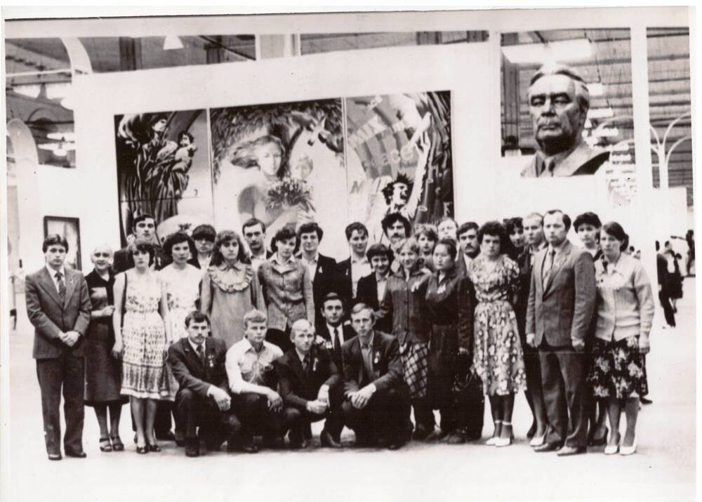 Фотография черно-белая групповая. Делегаты XIX съезда ВЛКСМ на фоне экспозиции на ВДНХ.