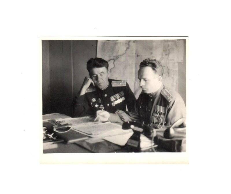 Фотография групповая. Комкор В.С. Лебедев и начальник штаба Тарасов изучают документы. Действующая армия.