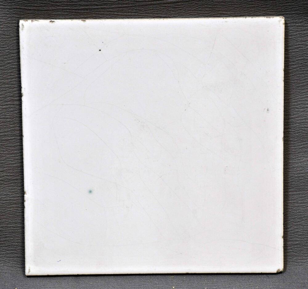 Плитка квадратной формы, с лицевой стороны белого цвета.