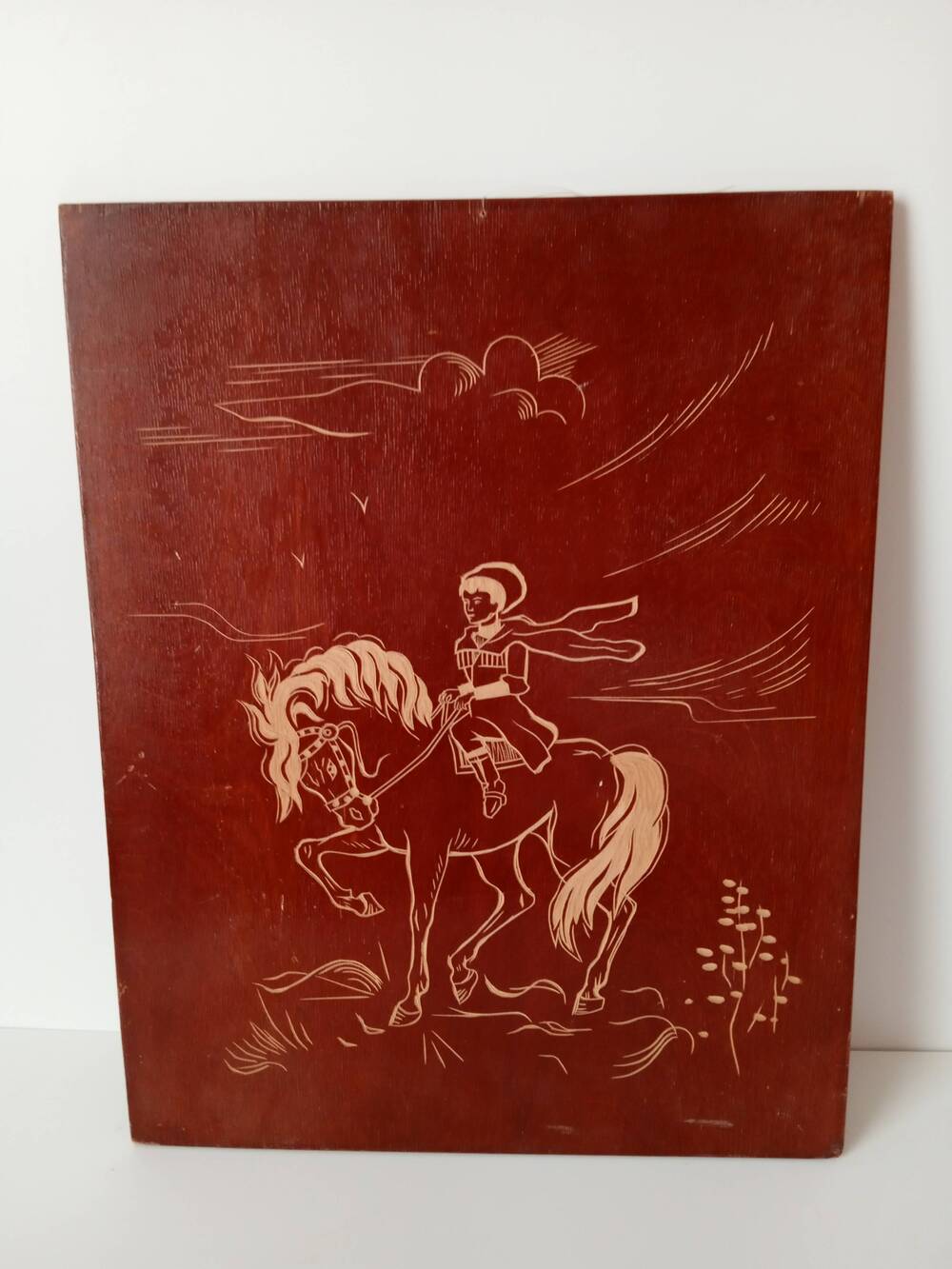 Картина на деревянной дощечке. Контурное изображение казака  на коне на коричневом фоне.