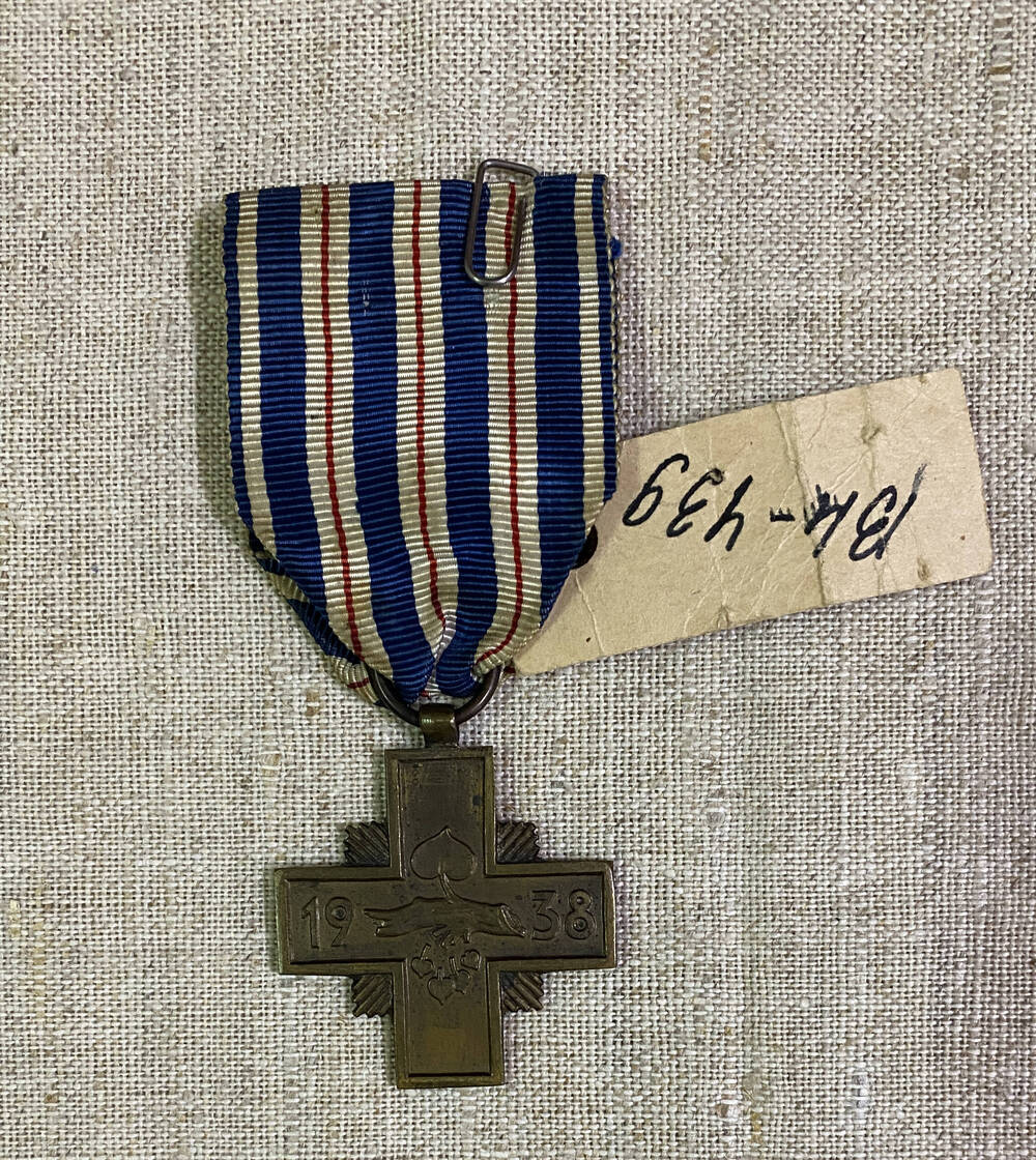 Орден в форме креста За верную службу с изображением силуэта дерева, листьев, цифры 1938 -  на аверсе; на реверсе -  буквы NSC. на муаровой ленте