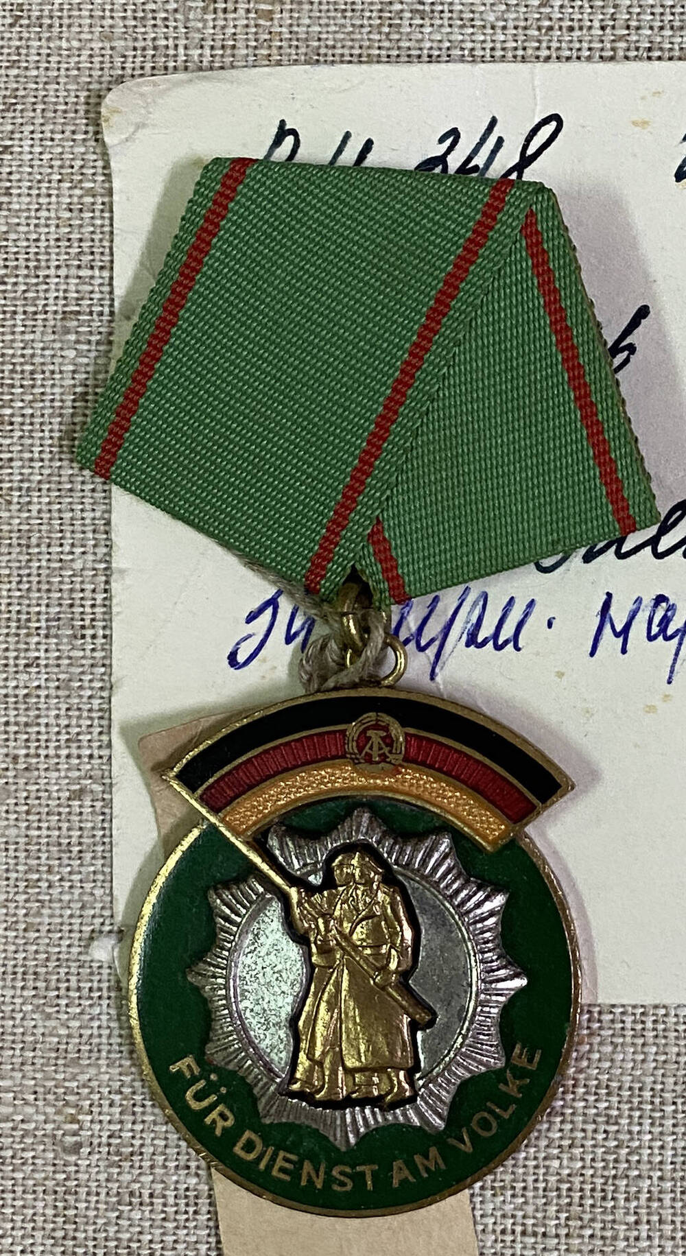 Медаль ГДР неправильной формы, в центре силуэт двух воинов держащих знамя, внизу текст; на муаровой ленте