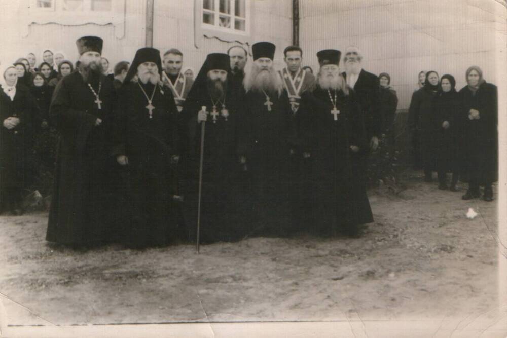 Фотография групповая в полный рост. На переднем плане (в центре) Иркутский Епископ Вениамин, первый справа -  отец Пётр. На заднем плане – служащие церкви и прихожане.