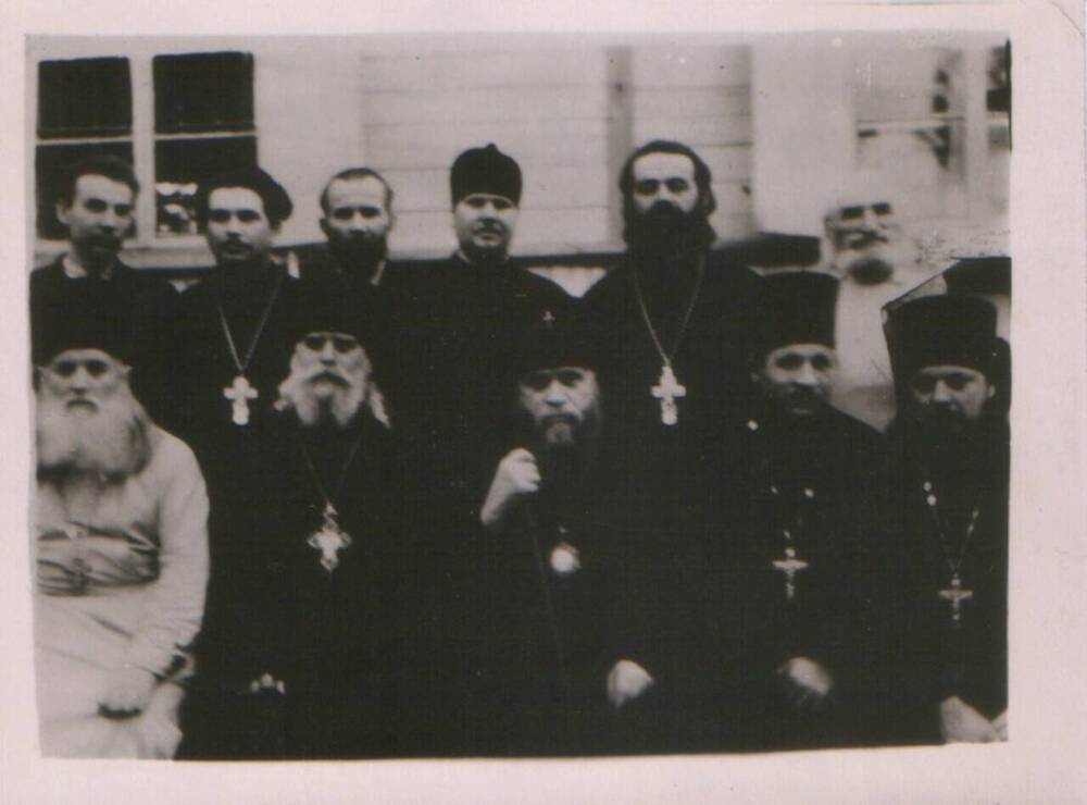 Фотография групповая в положении сидя и в рост. Первый слева (в белом подряснике) отец Пётр, третий – епископ Вениамин.