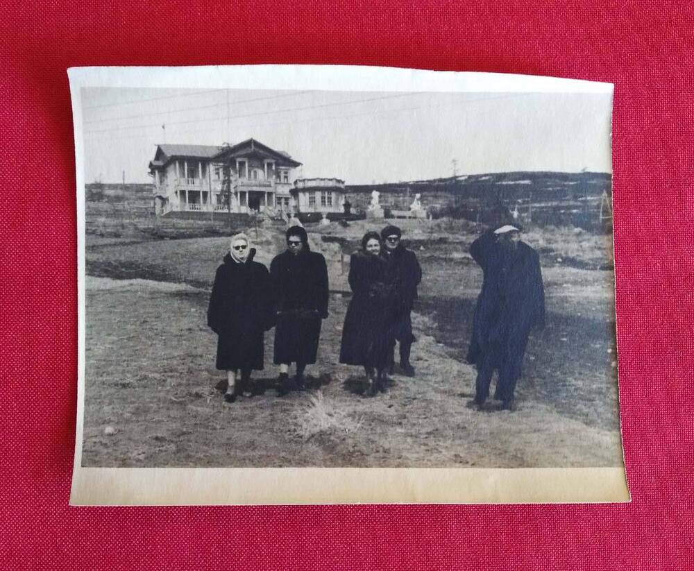 Фотография в черно-белом цвете Группа людей, на заднем плане Дом отдыха Горняк (Магадан), на обороте имеется рукописная надпись