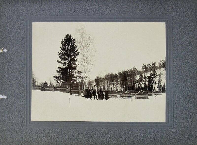 Фотография. Группа людей на фоне штабелей из шпал, в зимний период. На паспарту. Из коллекции «Строительство железной дороги Ачинск - Минусинск».