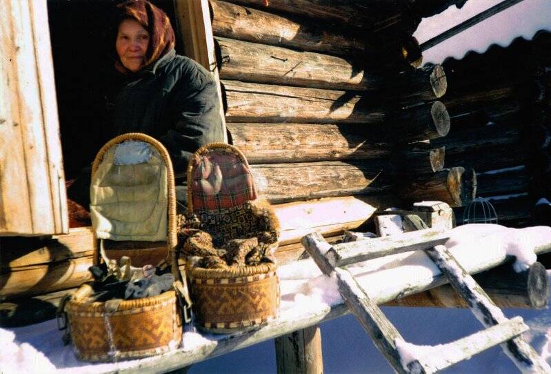 Фотография цветная, глянцевая. Этнографический артефакт. Женщина-манси, демонстрирует традиционные дневные колыбели.