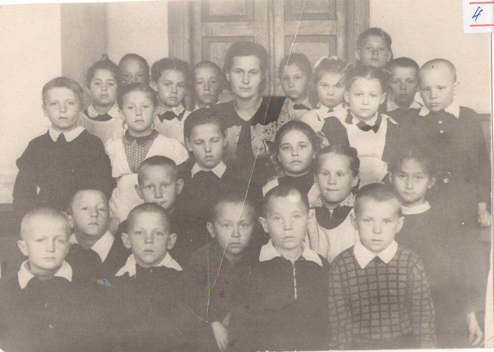 Фотография чёрно-белая, горизонтальная, прямоугольная. Композиционный групповой портрет учеников 1-го класса Тындинской средней школы. 1954г.