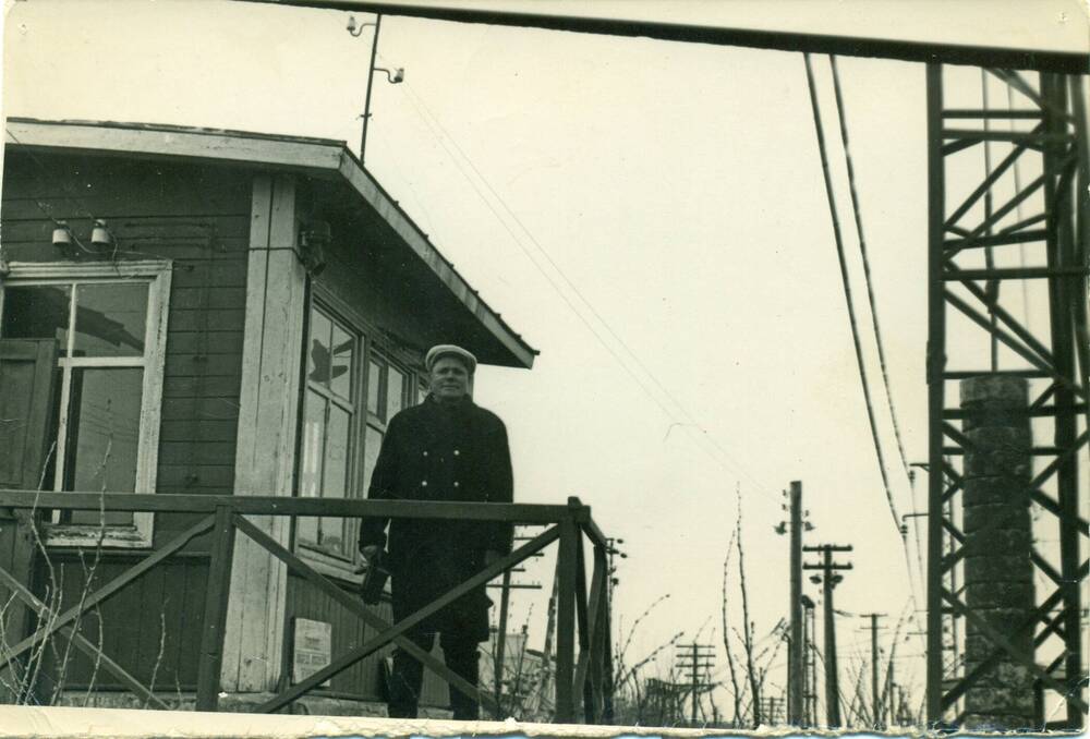 Фотография чёрно-белая: ж/д станция Любинская, стоит Кулишкин у здания ж/д переезда.